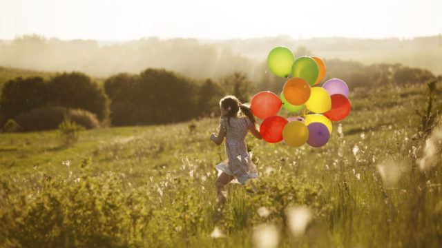 Girl in field with balloons symbolising the improved prospects of using a Chartered Financial Planner