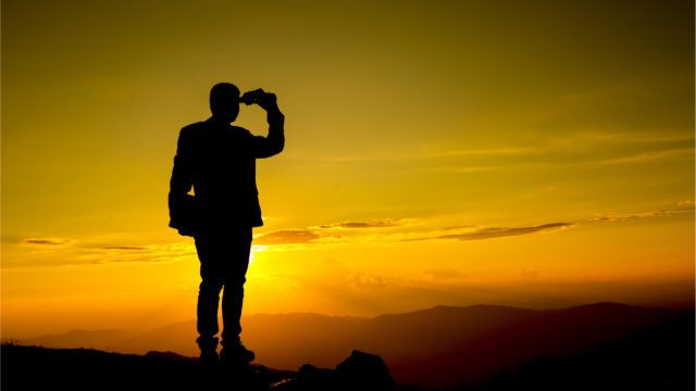 Business on hill with binoculars looking forward