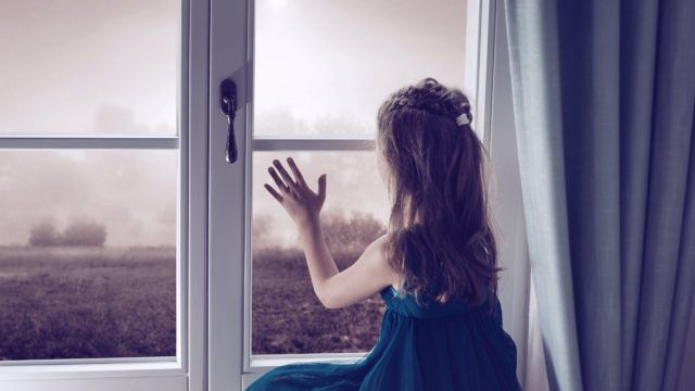 Miserable child looking through window