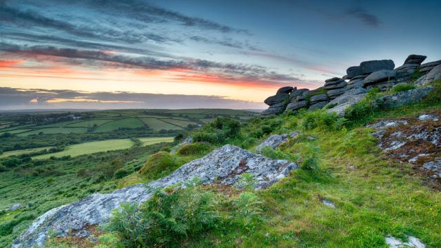 Sunset over a granite tor on moorland in Cornwall
