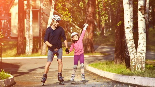 Dad with little daughter on the skates. two people rollerblade. sports family rollerskating outdoor