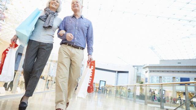 Happy Senior Couple Carrying Bags In Shopping Mall