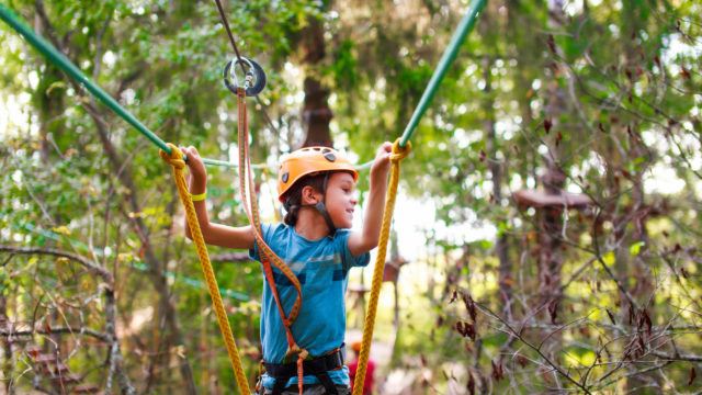 Boy making rope bridge cross with a safety net