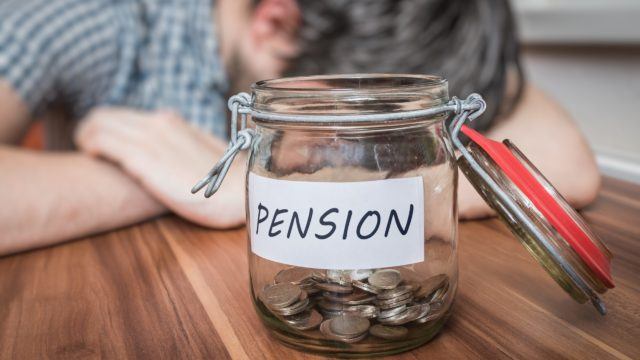 Depressed man lying on table. Pension savings in jar in front.