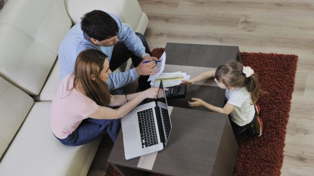 Parent's and child at laptop and with piggy bank savings