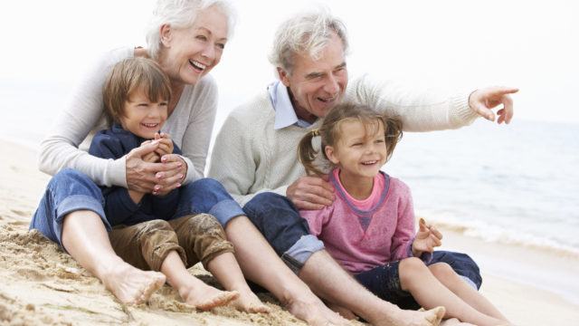 Grandparents And Grandchildren Sitting On Beach Together