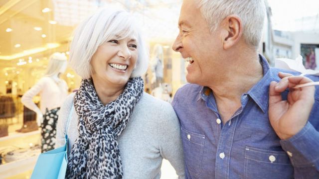 Happy Senior Couple Carrying Bags In Shopping Mall