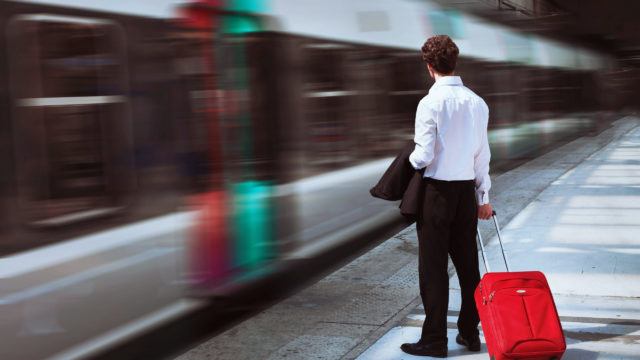 Businessman at train station as a train passes