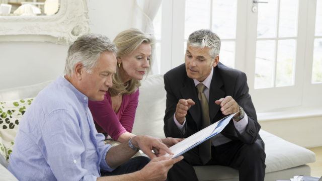 Mature couple sitting on sofa with financial advisor