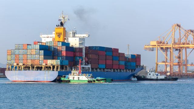 Cargo ship at the port arriving with push boat working