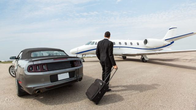 Businessman Standing By Car And Private Jet At Terminal