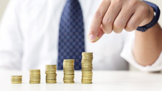 Business man's hand put money coins to stack of coins. Saving concept.