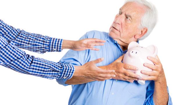 Senior man protecting piggy bank, savings from being stolen