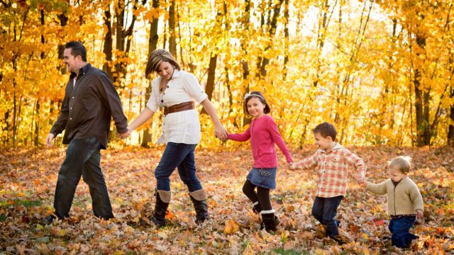 Family Holding Hands and Walking in Autumn Park