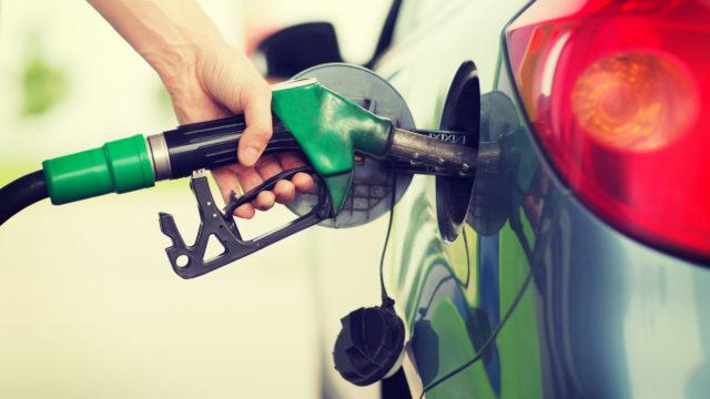 man pumping gasoline fuel in car at gas station