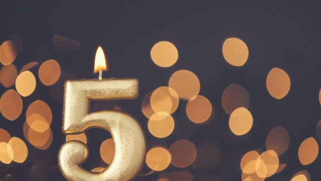 Gold number 5 celebration candle against blurred light background