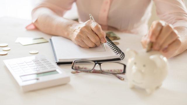 woman dropping money into piggy bank and doing accounts