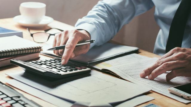 businessman working on desk with calculator