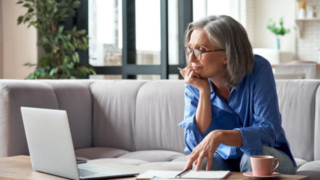 older woman at laptop with cup of coffee
