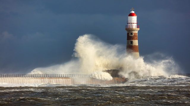 waves crashing against a lighthouse in a storm