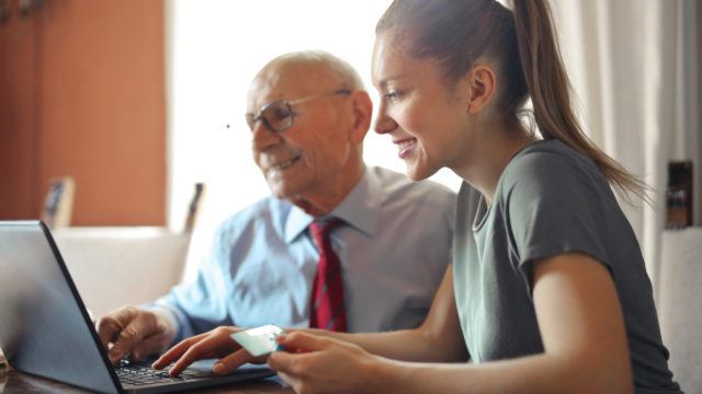 woman helps older man pay bills online