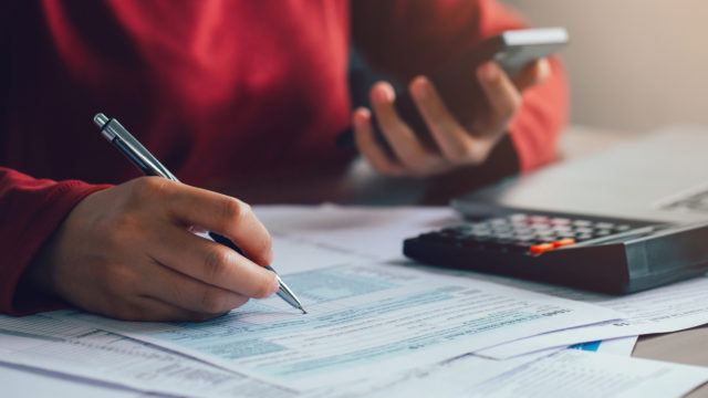 person at desk with calculator