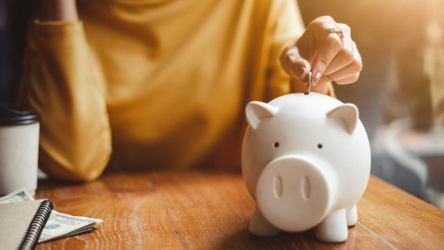 woman putting coin in piggy bank