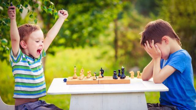 two boys playing chess, one has just won the game and is celebrating