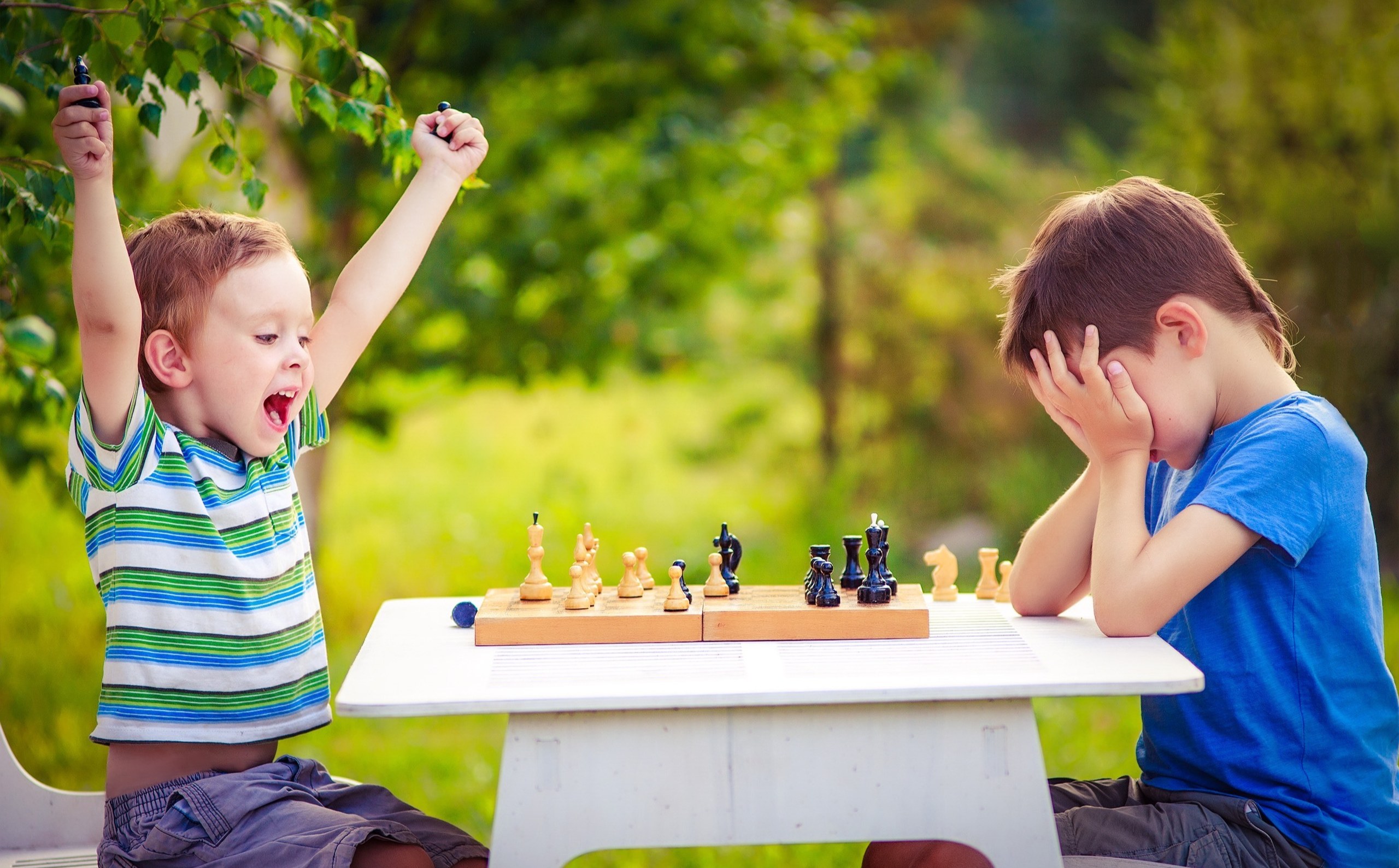 two boys playing chess, one has just won the game and is celebrating