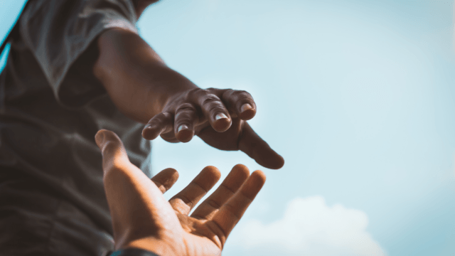 hand reaching down to help someone climb up