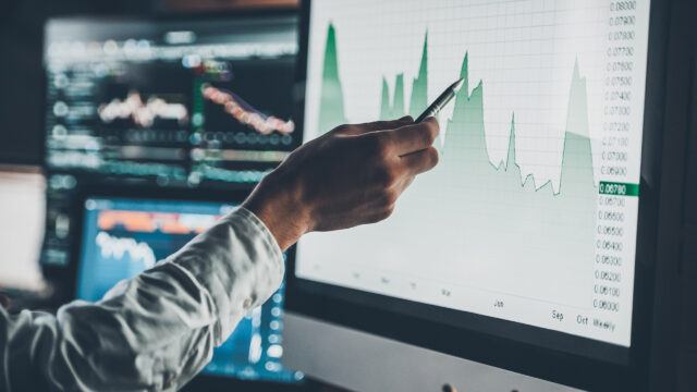 man pointing at multiple screens showing indices