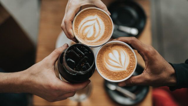 three people holding coffees in birds’ eye view