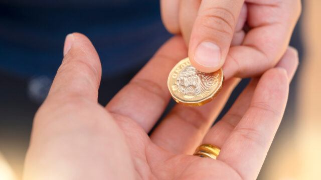 person passing £1 coin to another person