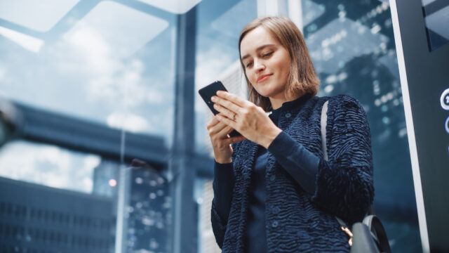 female investor checking her phone in a lift