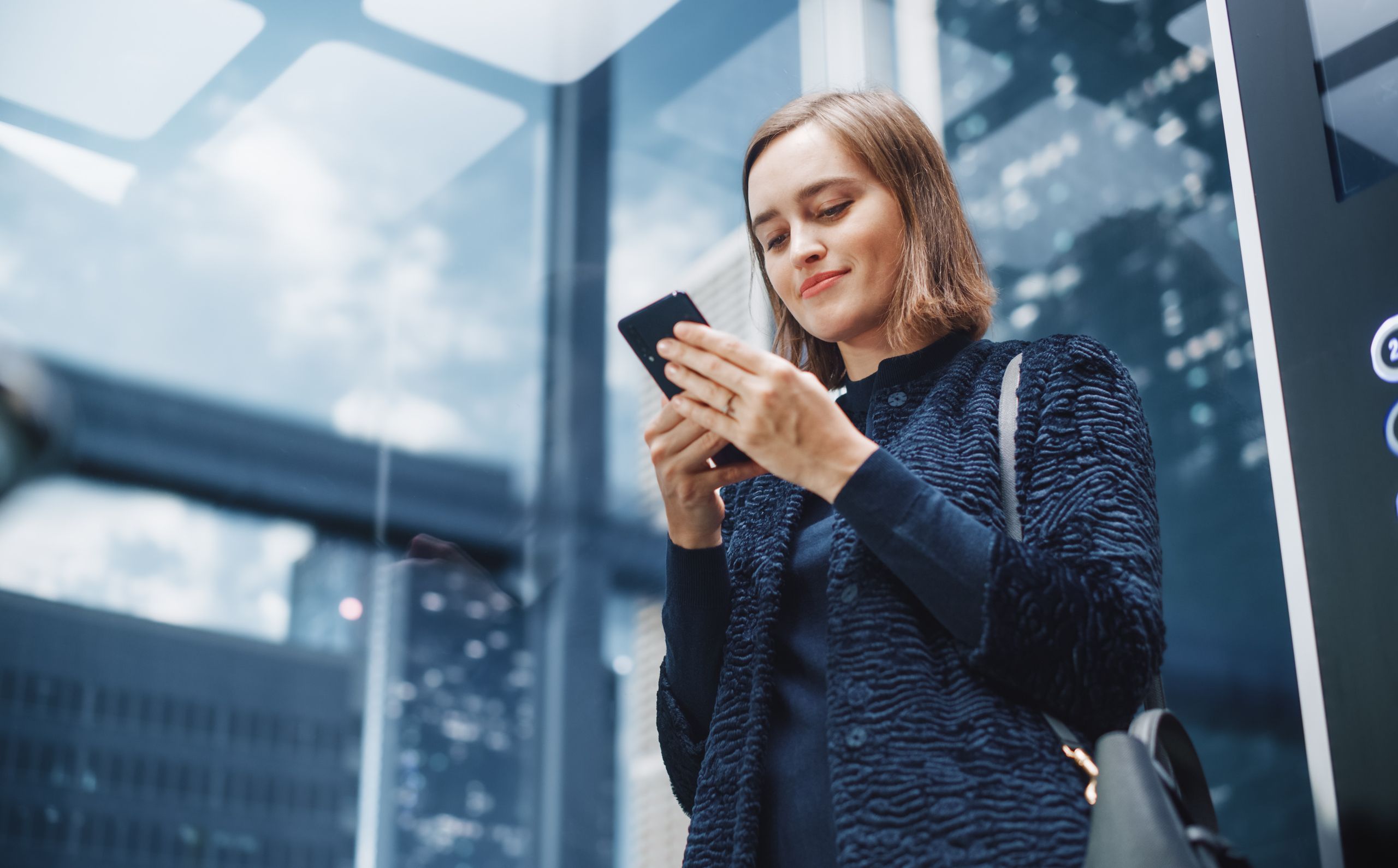 female investor checking her phone in a lift