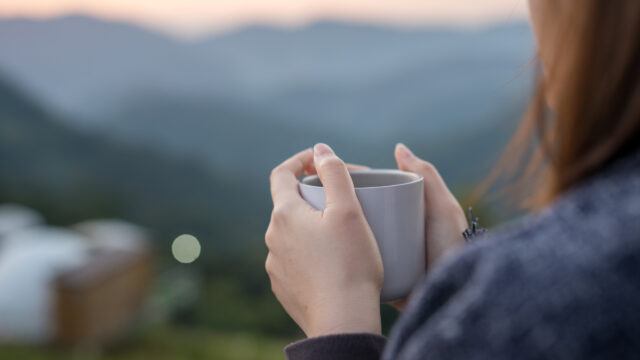 woman looking out at a pretty view with a cup of coffee