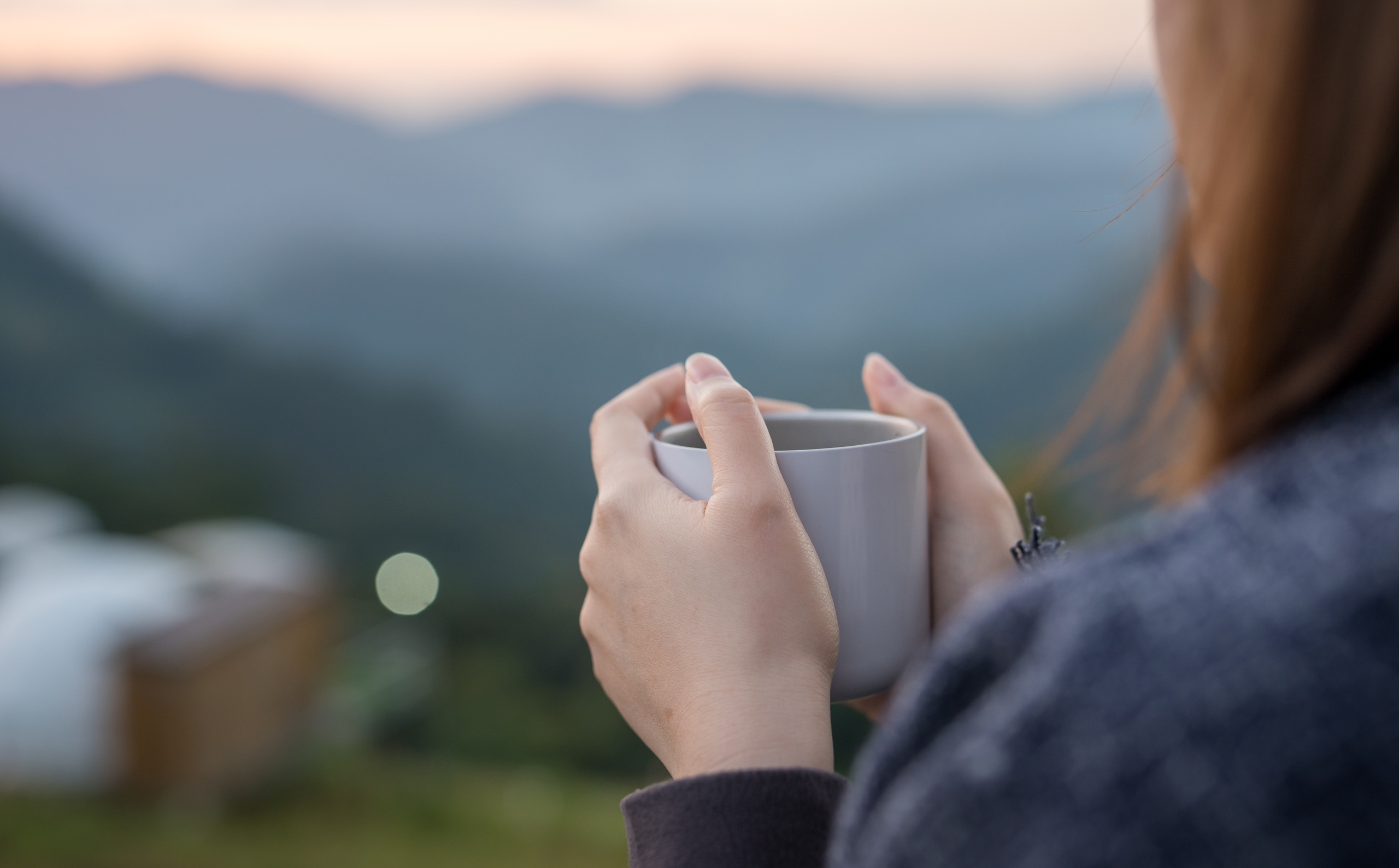 woman looking out at a pretty view with a cup of coffee
