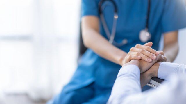 Nurse holding a patient’s hand