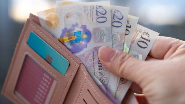 person holding wallet full of £20 and £10 notes